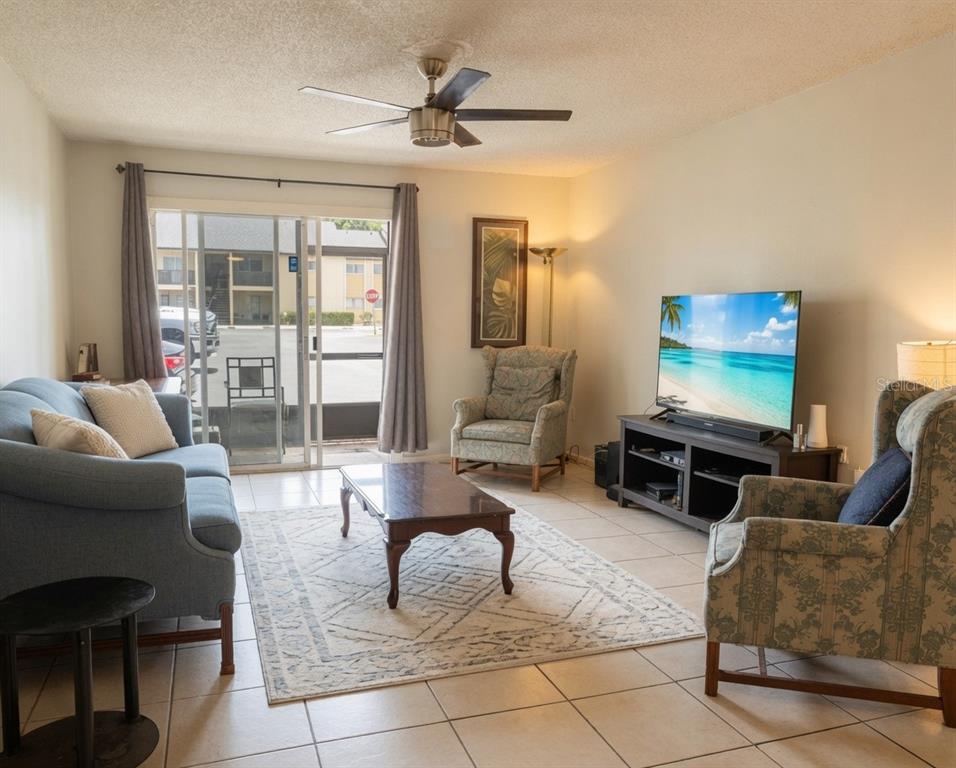 A living room features tile floors, a ceiling fan, a sofa, armchairs, and a sliding door — 918 LAKE DESTINY ROAD UNIT A, ALTAMONTE SPRINGS, FL