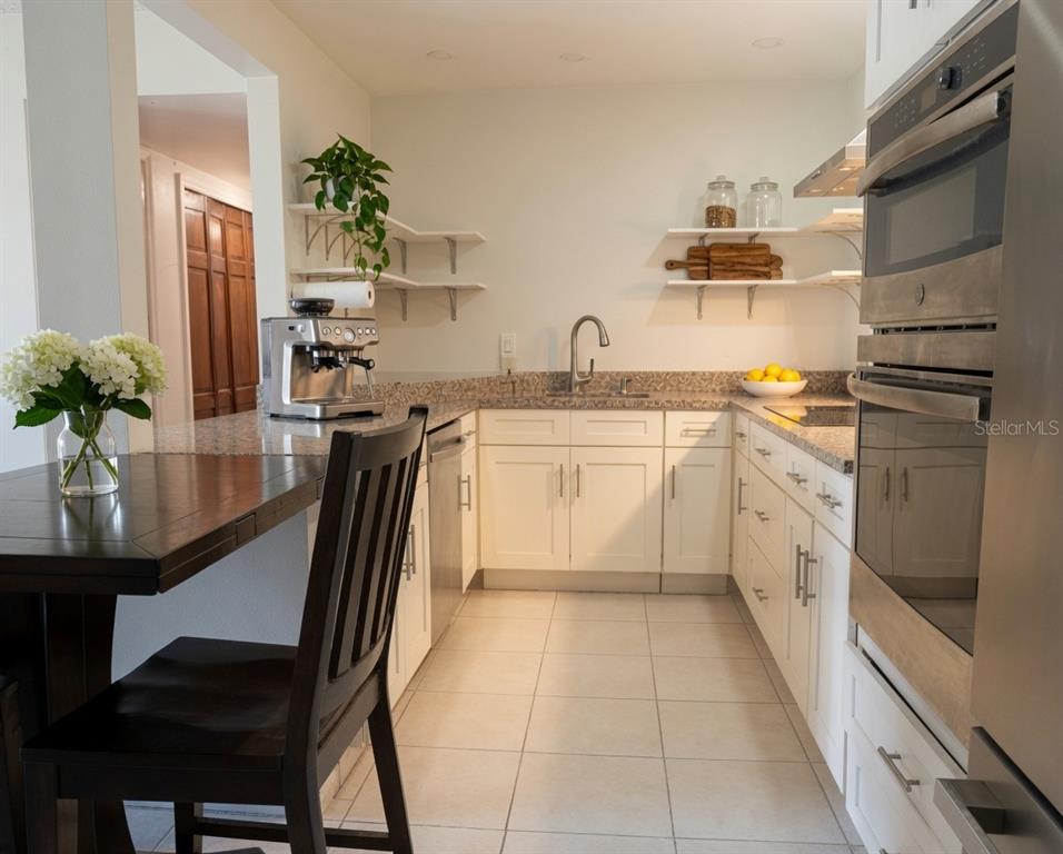 A kitchen features white cabinets, granite countertops, stainless steel appliances, and an attached dining table — 918 LAKE DESTINY ROAD UNIT A, ALTAMONTE SPRINGS, FL