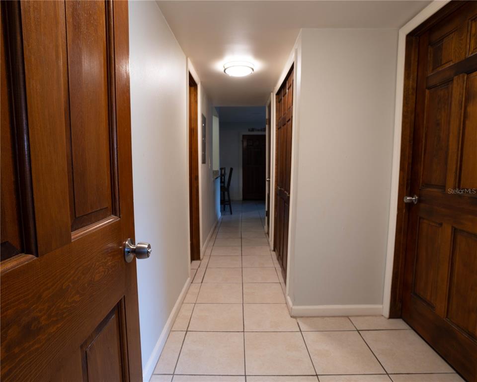 A hallway with light-colored tile flooring, white walls, and several wooden doors — 918 LAKE DESTINY ROAD UNIT A, ALTAMONTE SPRINGS, FL