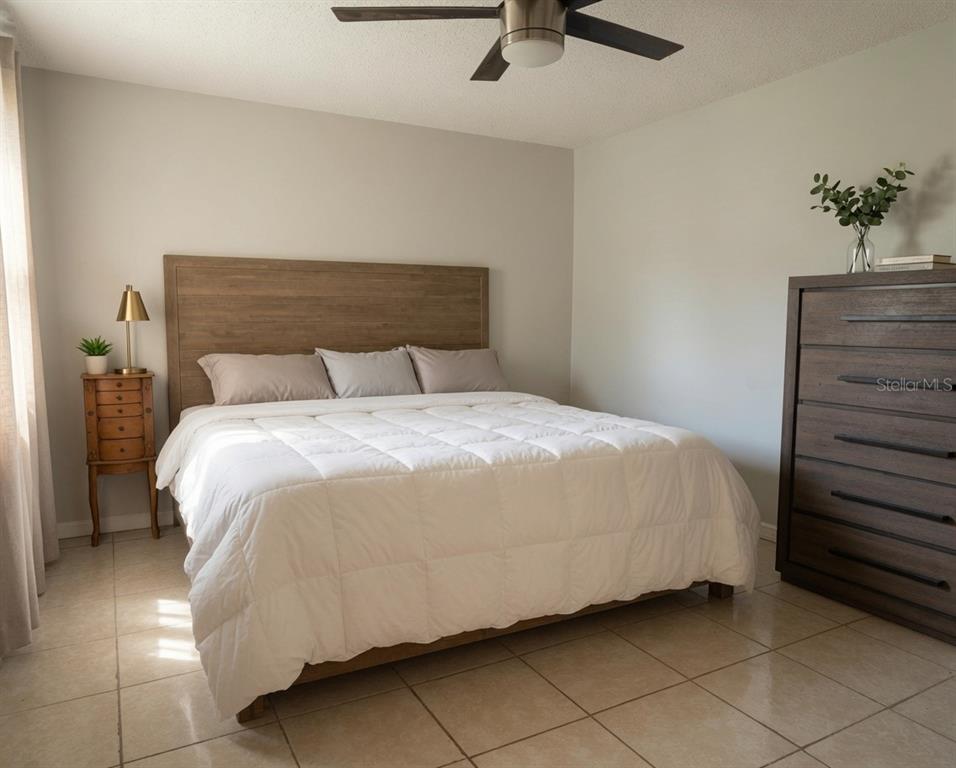 A bedroom features a wooden bed frame, white bedding, a tall dresser, and tile flooring — 918 LAKE DESTINY ROAD UNIT A, ALTAMONTE SPRINGS, FL