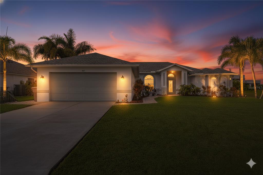 A single-story house with a two-car garage and palm trees at sunset — 430 NW 39TH AVENUE, CAPE CORAL, FL