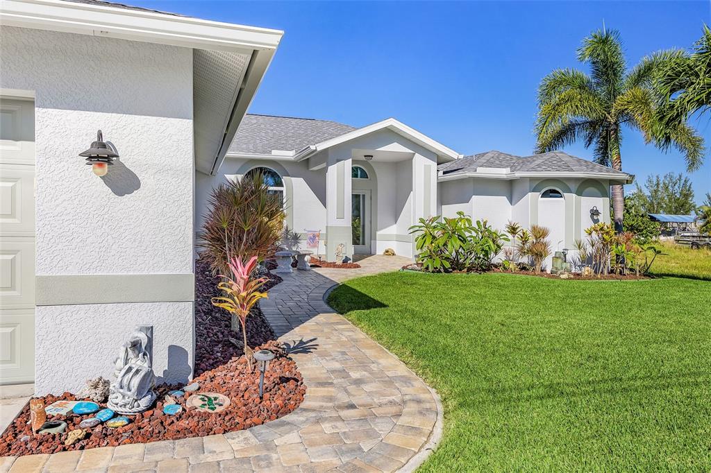 A paved walkway leads to the front entrance of a white house with a lawn — 430 NW 39TH AVENUE, CAPE CORAL, FL