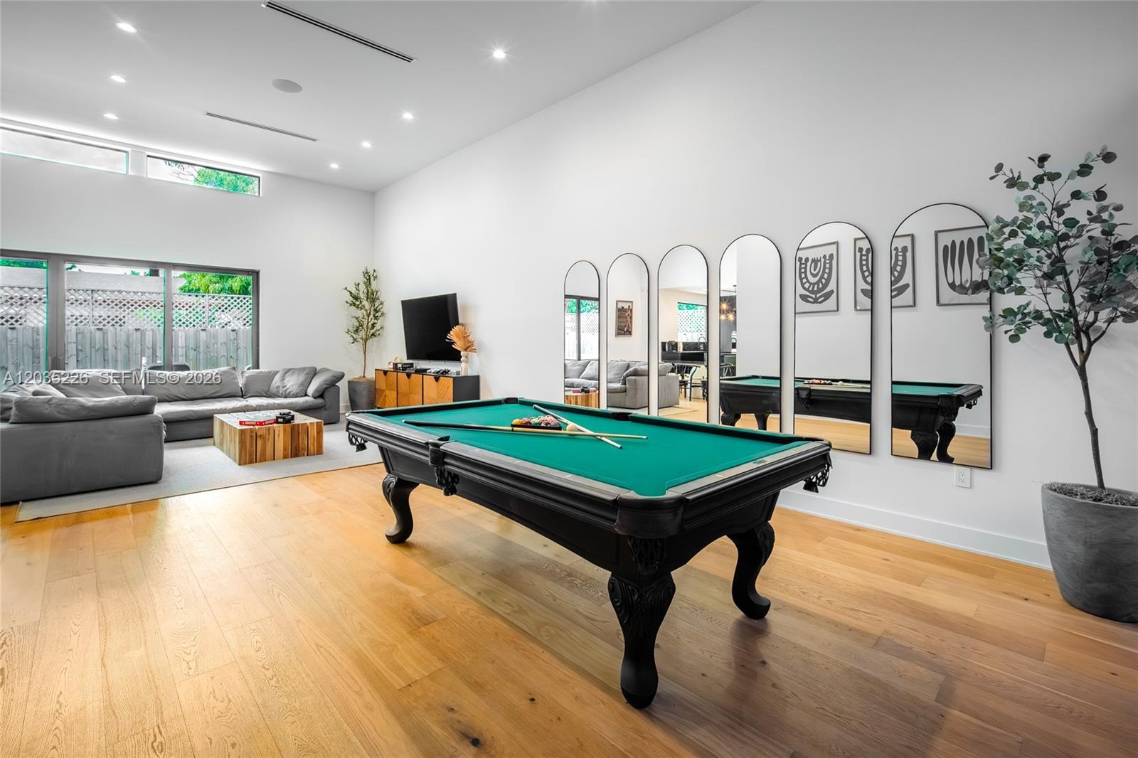 A spacious game room features a pool table, light wood floors, and arched wall mirrors — 243 NW 42nd St, Miami FL 33127, MIAMI, FL