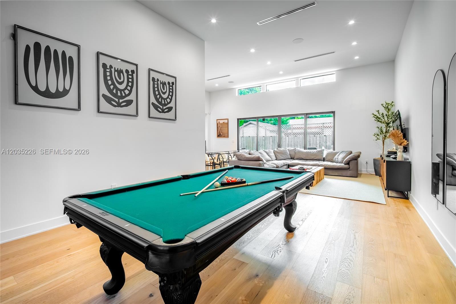 A spacious room features a green pool table, hardwood floors, and a seating area — 243 NW 42nd St, Miami FL 33127, MIAMI, FL