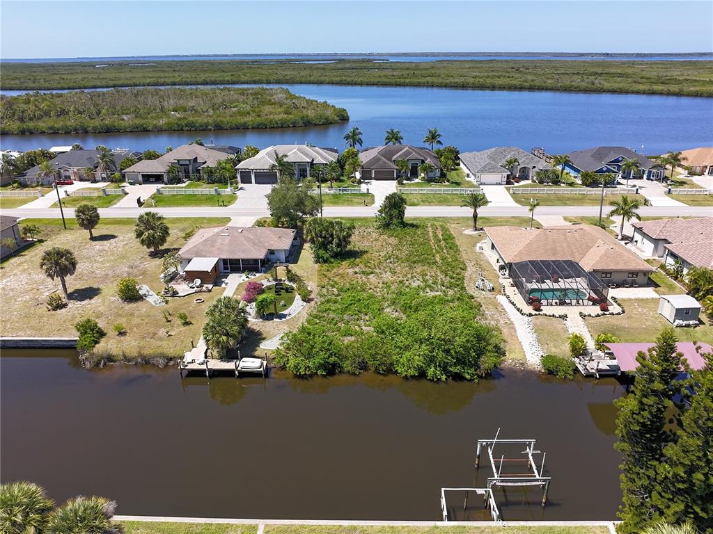An aerial view shows a vacant waterfront lot situated between two houses with docks — 17360 OHARA DRIVE, PORT CHARLOTTE, FL