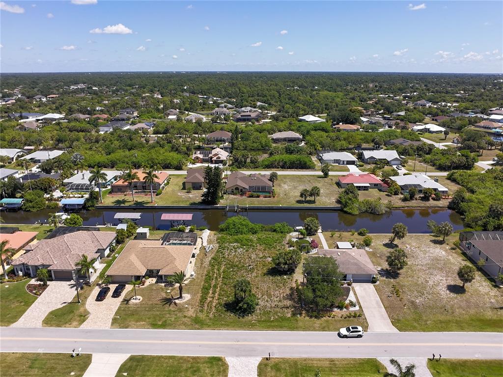 An aerial view shows a vacant residential lot situated between two houses along a canal — 17360 OHARA DRIVE, PORT CHARLOTTE, FL