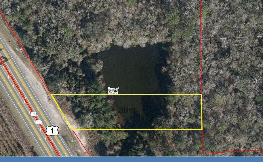 An aerial view shows a rectangular plot of land containing a pond near a highway — 3 US HWY 1, HILLIARD, FL