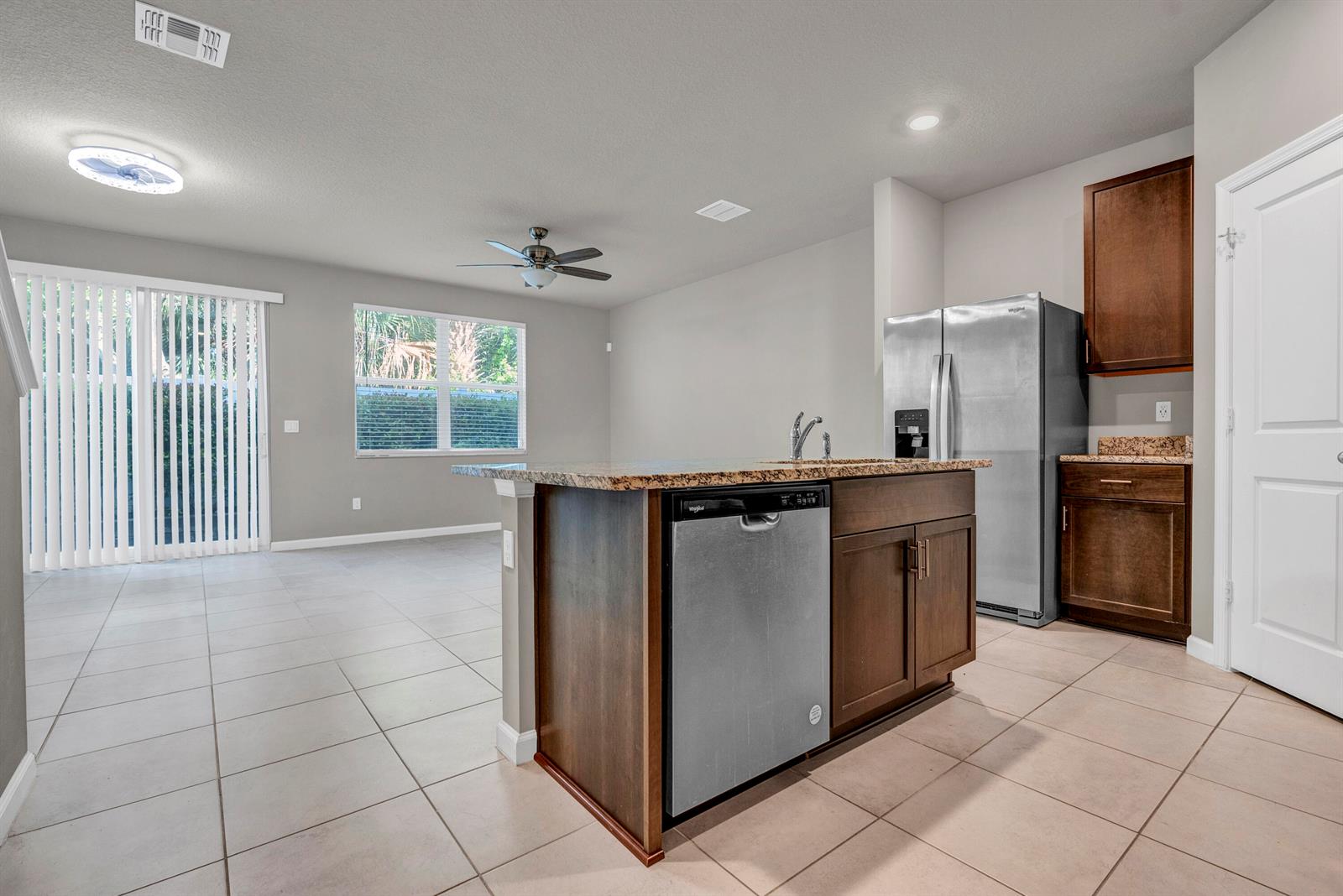A kitchen with a granite-topped island, stainless steel appliances, and tile flooring — 5659 Enclave Drive, Riviera Beach FL 33407, RIVIERA BEACH, FL