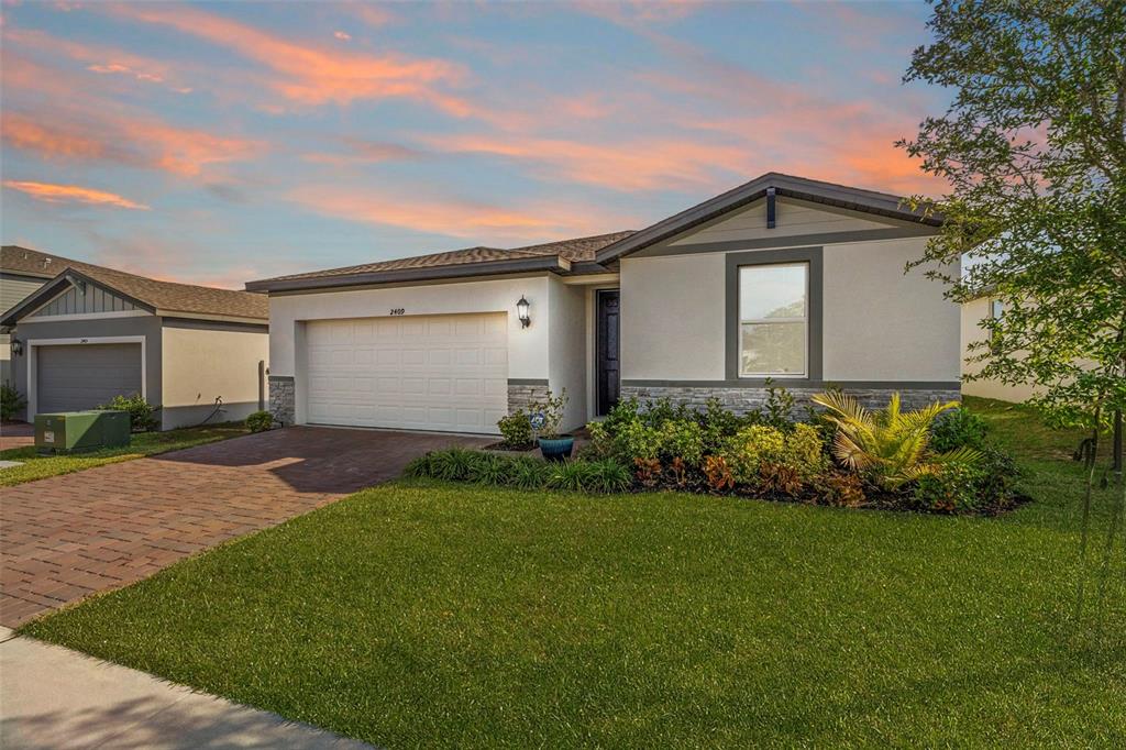 A single-story house with a white stucco facade, stone accents, and a paved driveway — 2409 WHITE TAIL STREET, DAVENPORT, FL