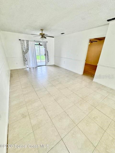 A living room features light-colored tile flooring, white walls with chair rail molding, and curtains — 1220 CHENEY HIGHWAY UNIT D, TITUSVILLE, FL