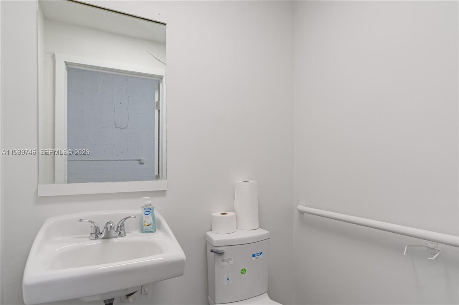 A small bathroom features a white wall-mounted sink, a toilet, and a grab bar — 453 W 28th St, Hialeah FL 33010, HIALEAH, FL