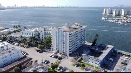 An aerial view shows a multi-story apartment building situated along a waterfront with parked cars — 2016 Bay Dr # 202, Miami Beach FL 33141, MIAMI BEACH, FL