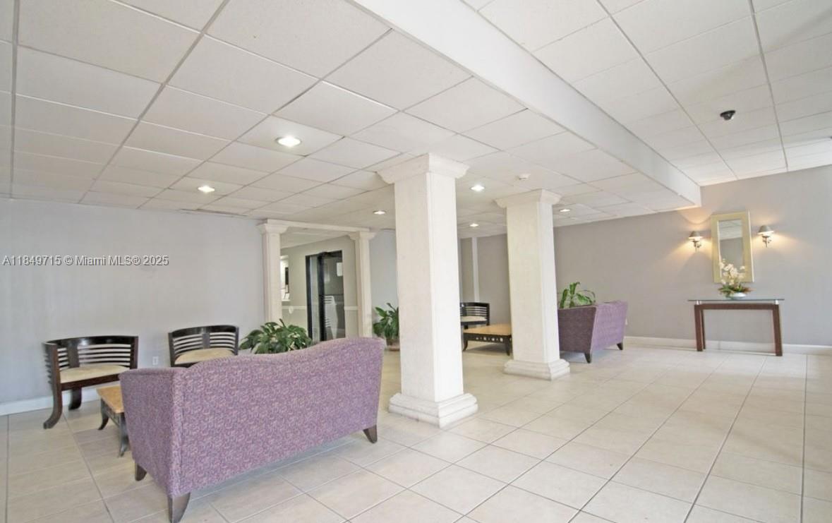 A lobby area features tiled floors, a drop ceiling, two white columns, and purple sofas — 2016 Bay Dr # 202, Miami Beach FL 33141, MIAMI BEACH, FL