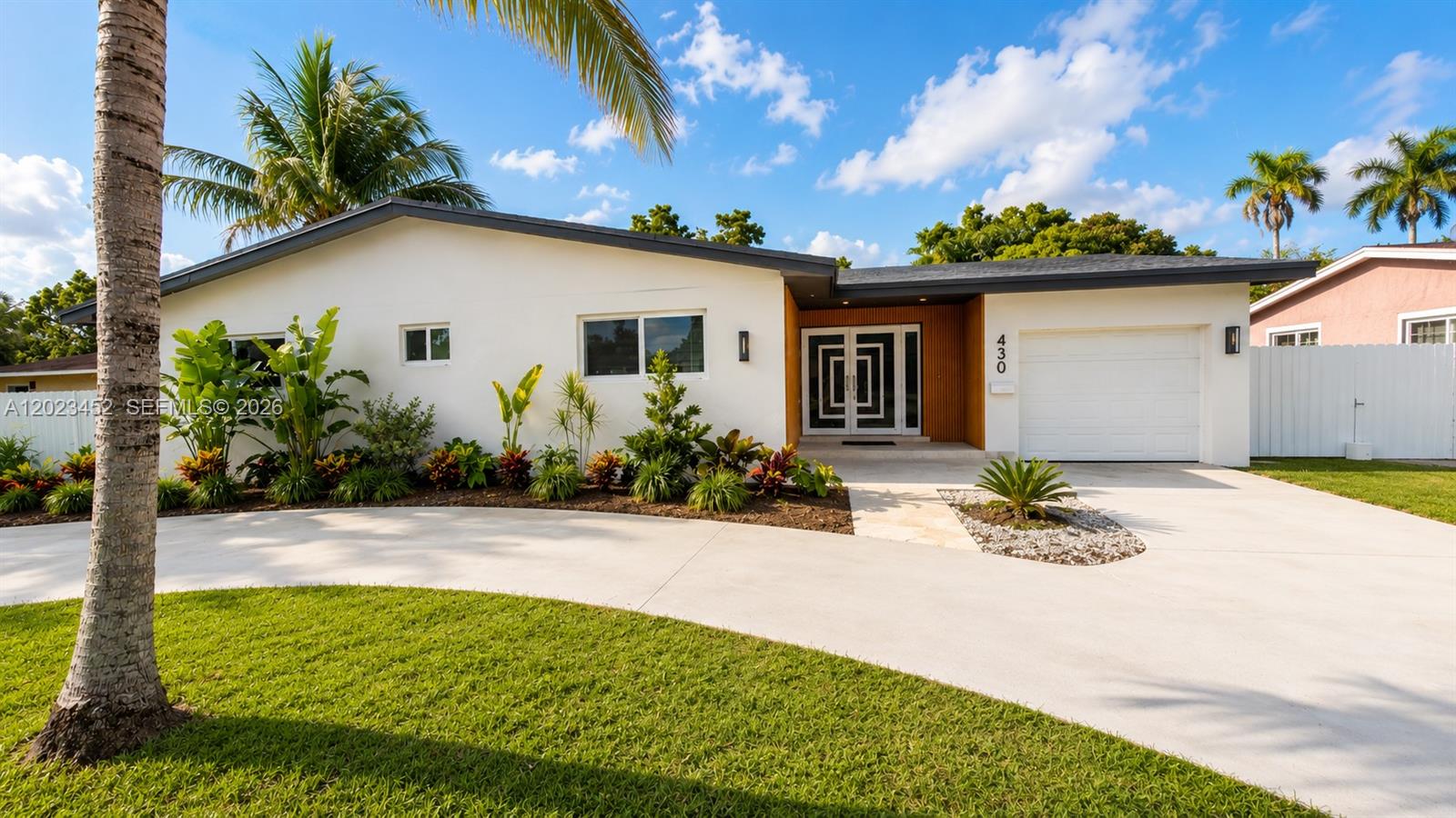 A single-story house with a white exterior, a curved driveway, and a modern front entrance — 430 NE 145th St, Miami FL 33161, MIAMI, FL