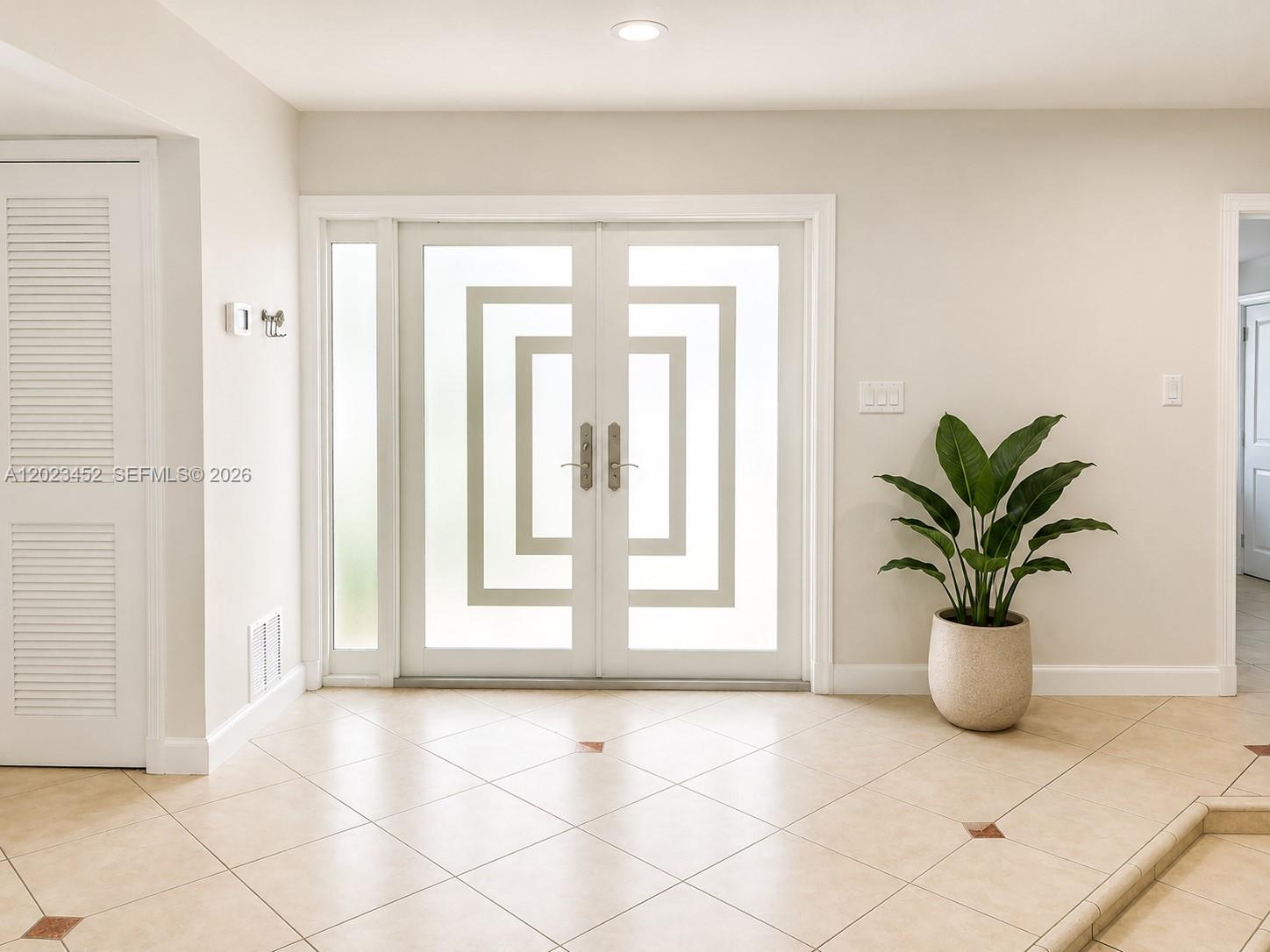 A bright entryway features double glass doors with geometric patterns and light tile flooring — 430 NE 145th St, Miami FL 33161, MIAMI, FL