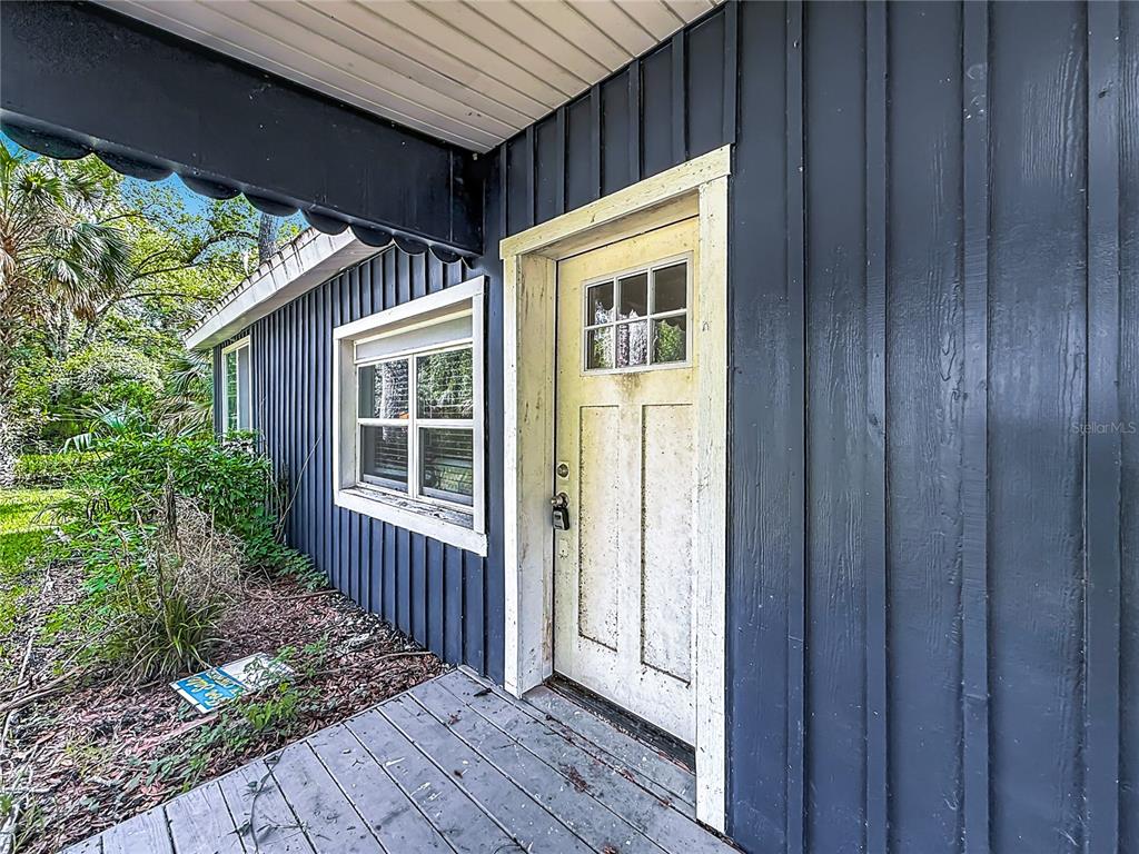 A dark blue vertical-sided house exterior features a white-trimmed door and a wooden porch — 5360 S ELM AVENUE, HOMOSASSA, FL