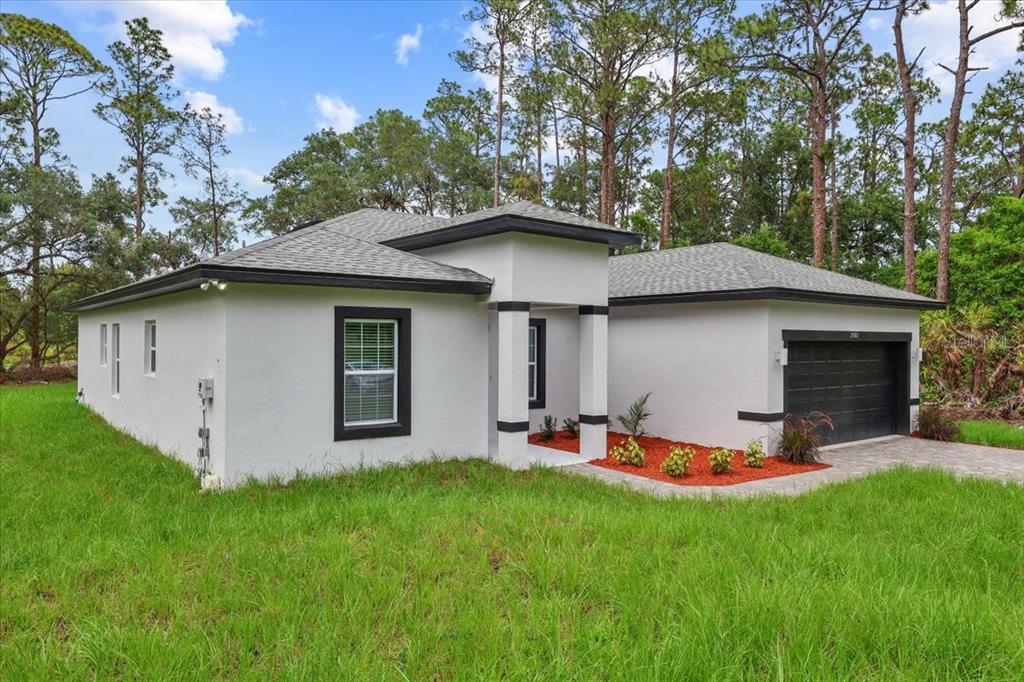 A single-story white stucco house with a dark roof and garage sits on a lawn — 2580 PLUMOSA DRIVE, INDIAN LAKE ESTATES, FL