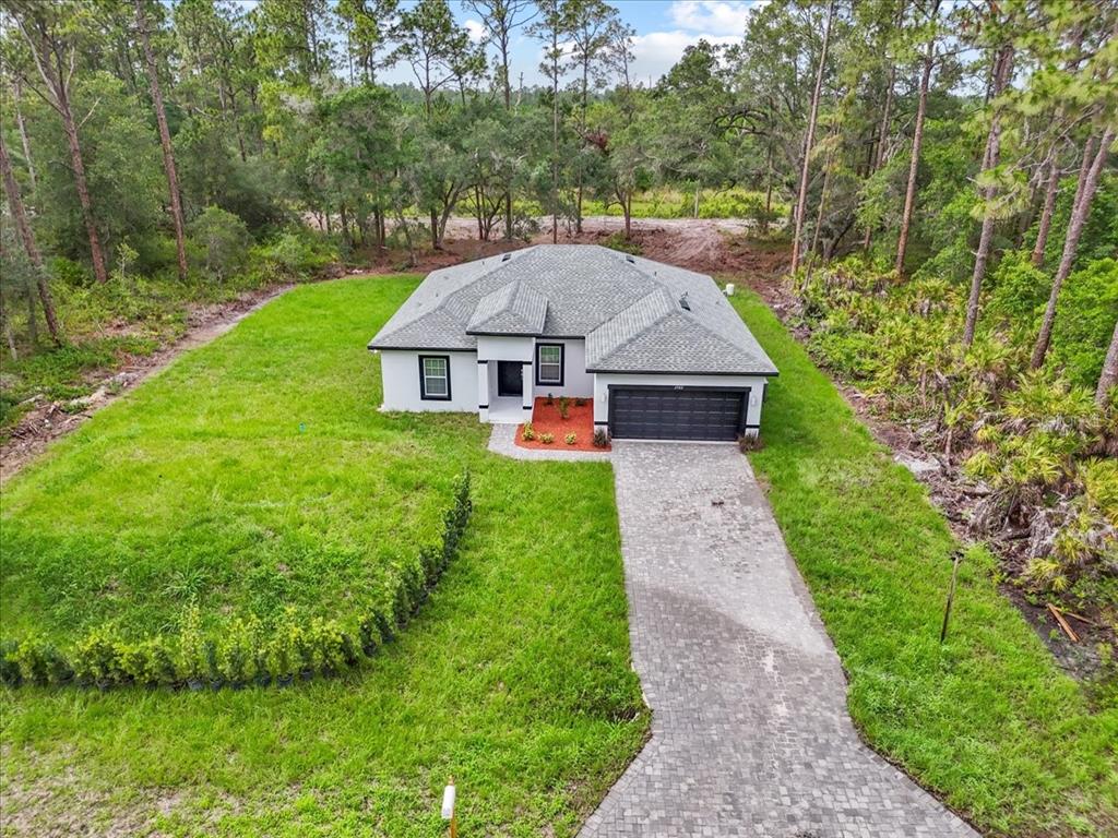 An aerial view shows a single-story house with a gray roof and a paved driveway — 2580 PLUMOSA DRIVE, INDIAN LAKE ESTATES, FL