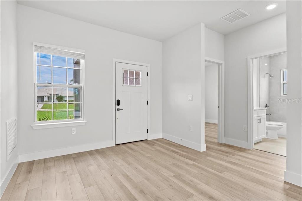 A room with light wood-look flooring, a white door, a window, and an attached bathroom — 2580 PLUMOSA DRIVE, INDIAN LAKE ESTATES, FL
