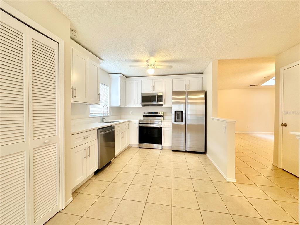 A kitchen with white cabinets, stainless steel appliances, and light-colored tile flooring — 1622 CIMARRON HILLS DRIVE, APOPKA, FL