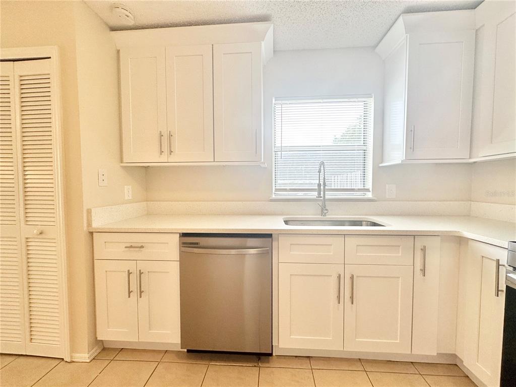 A kitchen features white cabinets, stainless steel appliances, a sink, and light-colored countertops — 1622 CIMARRON HILLS DRIVE, APOPKA, FL
