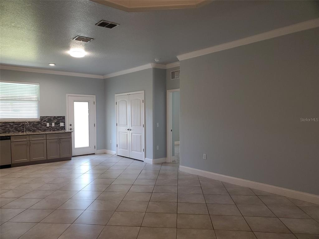 A room with light blue walls, tile flooring, a small kitchenette, and white double doors — 7 EMPIRE LANE UNIT B, PALM COAST, FL