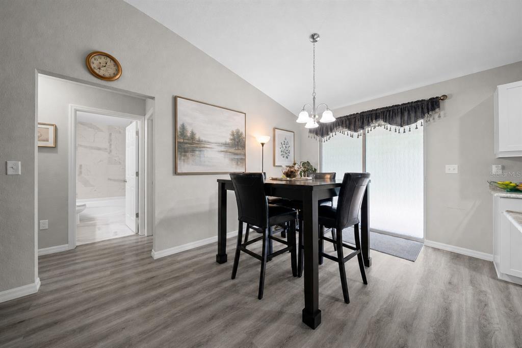 A kitchen features white cabinets, granite countertops, stainless steel appliances, and light wood-look flooring — 13358 SW 111TH STREET, DUNNELLON, FL
