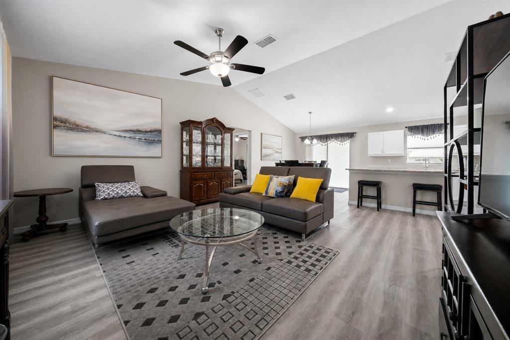 A dining area with gray wood-look flooring, a vaulted ceiling, and a sliding glass door — 13358 SW 111TH STREET, DUNNELLON, FL