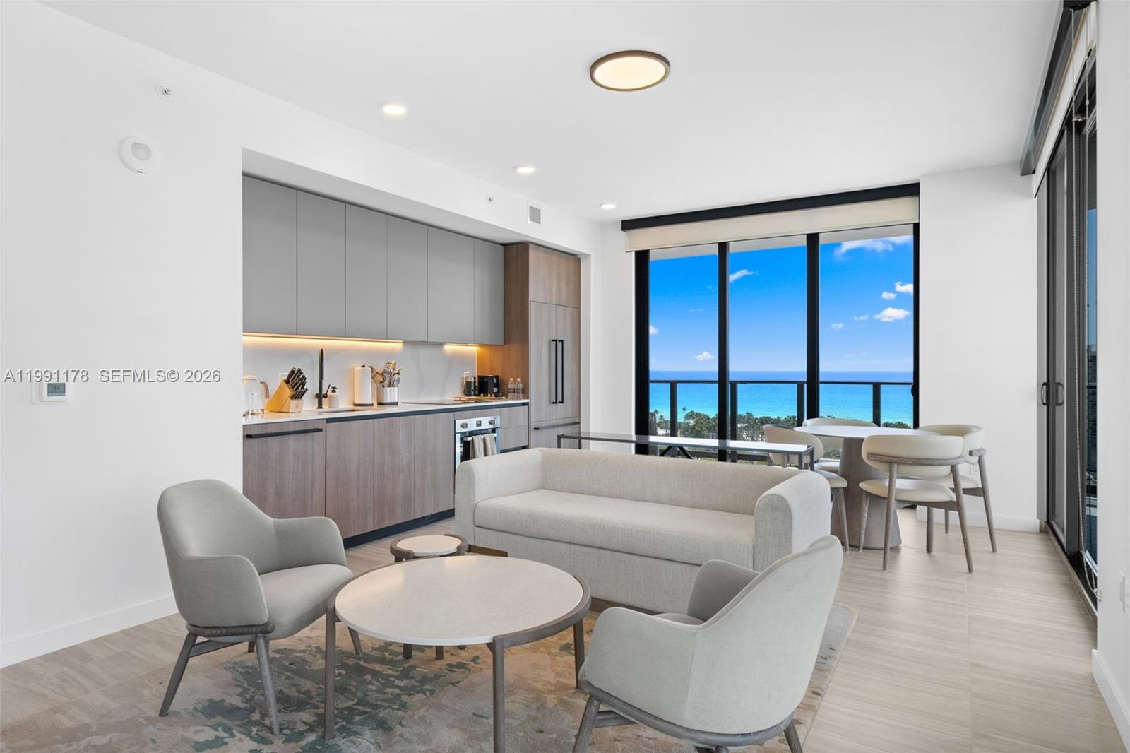 A modern open-concept living area features a kitchen, seating area, and floor-to-ceiling ocean views — 580 72nd St # 1402, Miami Beach FL 33141, MIAMI BEACH, FL
