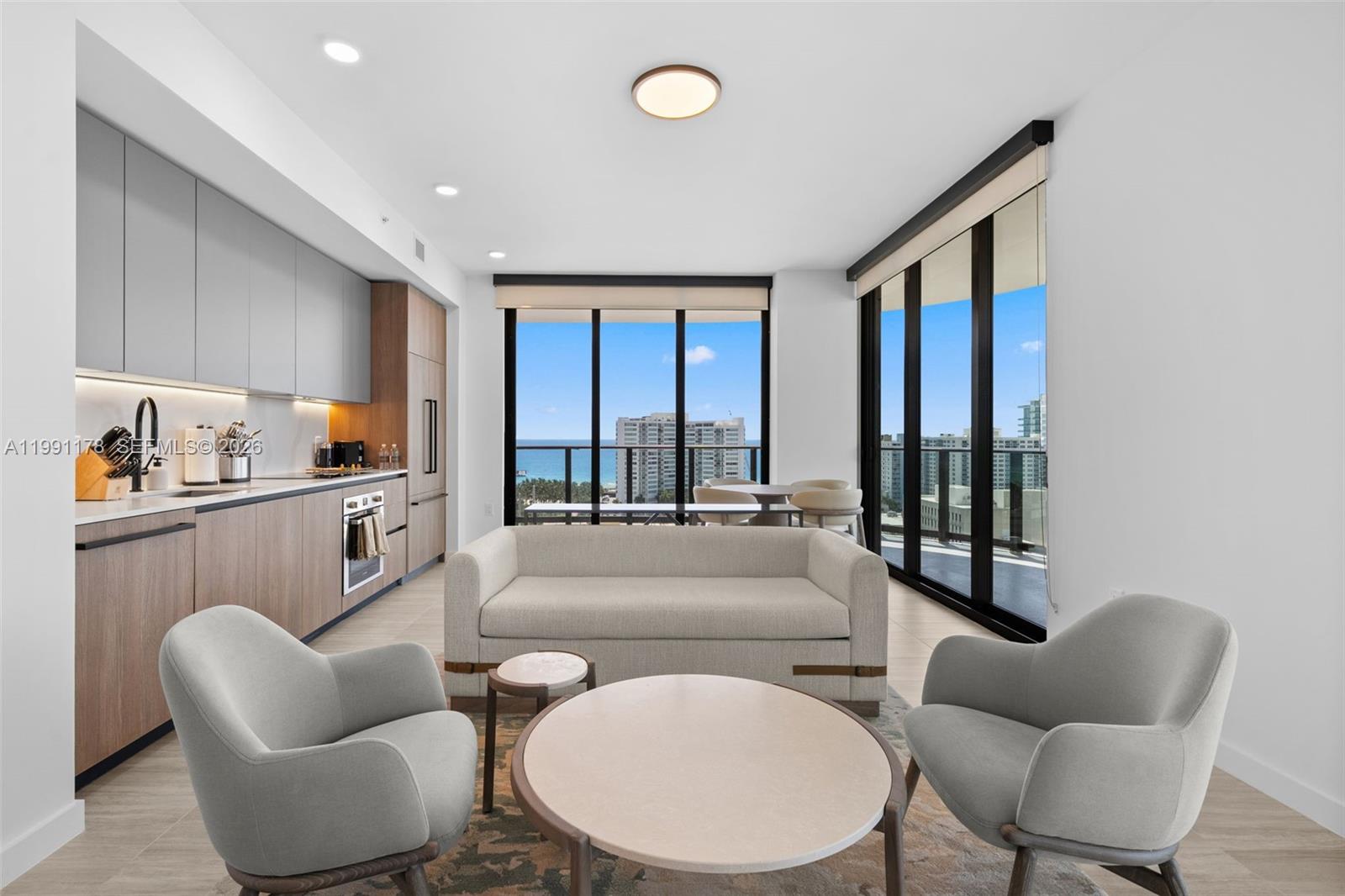 A modern open-concept living room and kitchen area features floor-to-ceiling windows with ocean views — 580 72nd St # 1402, Miami Beach FL 33141, MIAMI BEACH, FL
