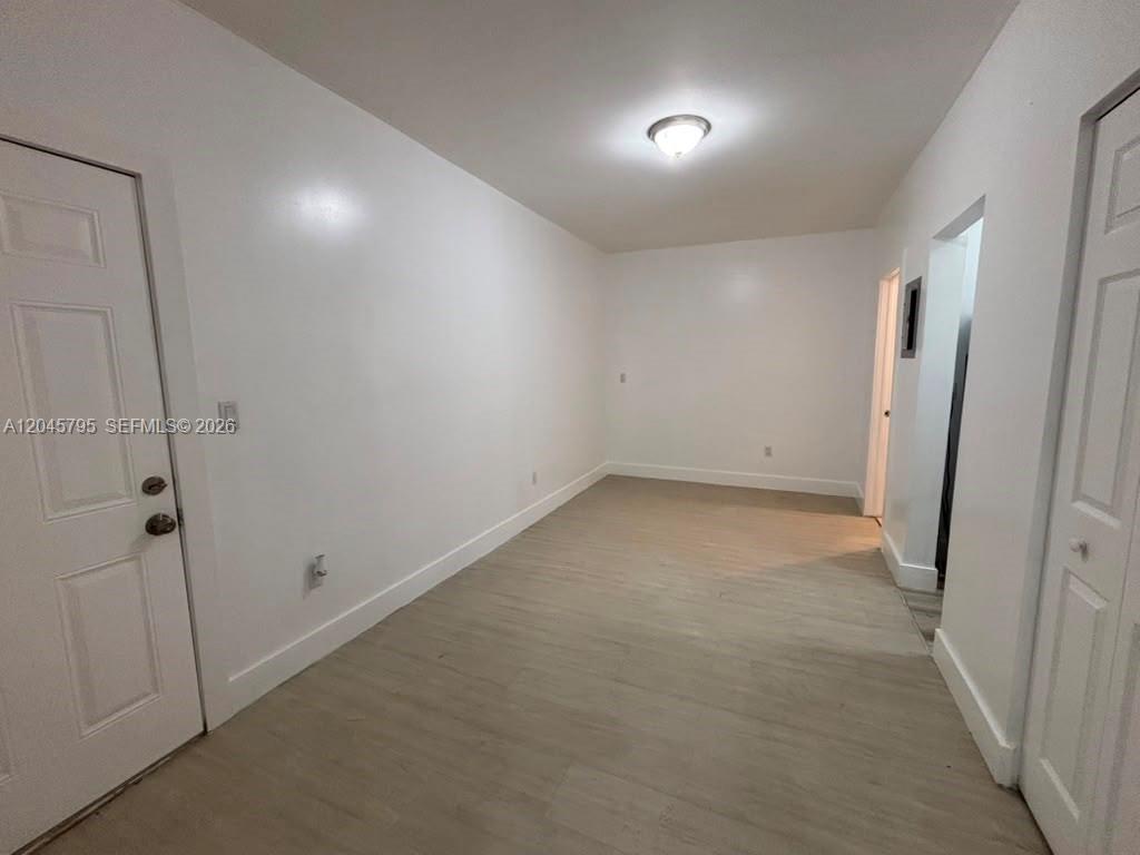 An empty room features white walls, light-colored wood-look flooring, and a ceiling light fixture — 1051 NW 2nd St # 15, Miami FL 33128, MIAMI, FL