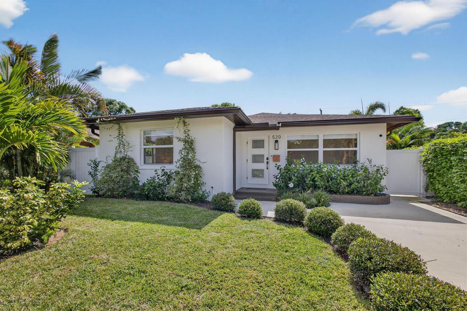 A single-story white house with a flat roof, a front lawn, and a concrete driveway — 520 36th Street, West Palm Beach FL 33407, WEST PALM BEACH, FL