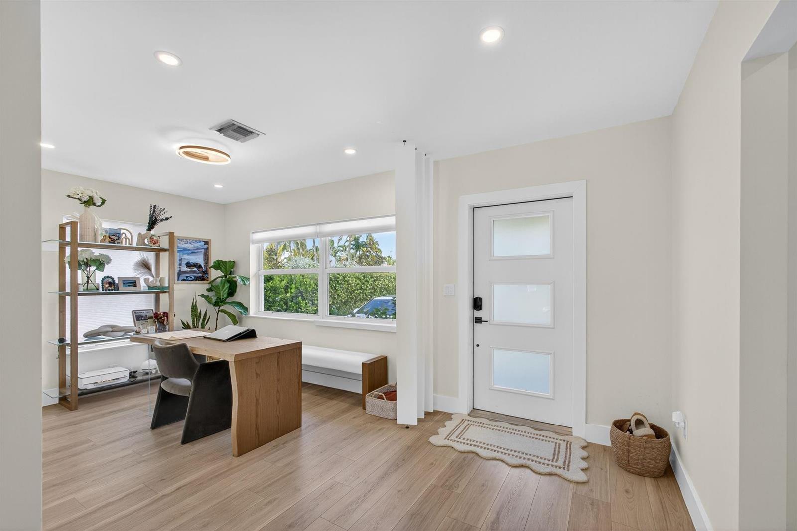 A home office with a wooden desk, shelving unit, and front door entrance — 520 36th Street, West Palm Beach FL 33407, WEST PALM BEACH, FL
