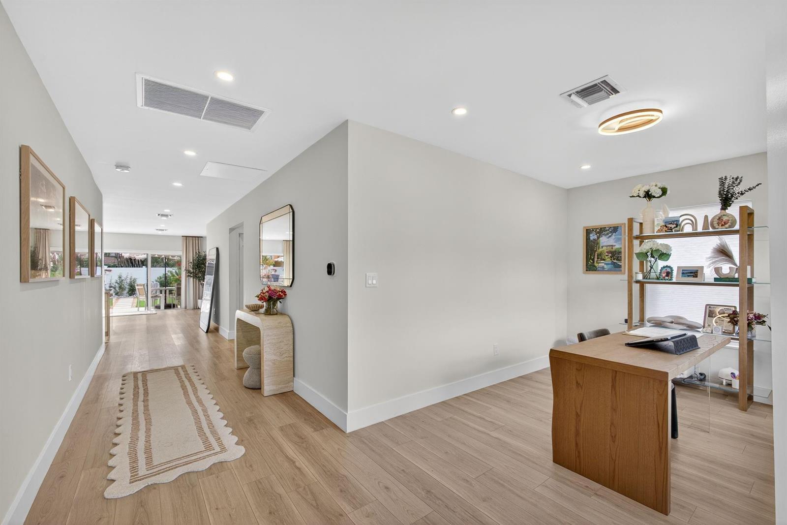 A bright home office with light wood flooring, a wooden desk, and an adjacent hallway — 520 36th Street, West Palm Beach FL 33407, WEST PALM BEACH, FL