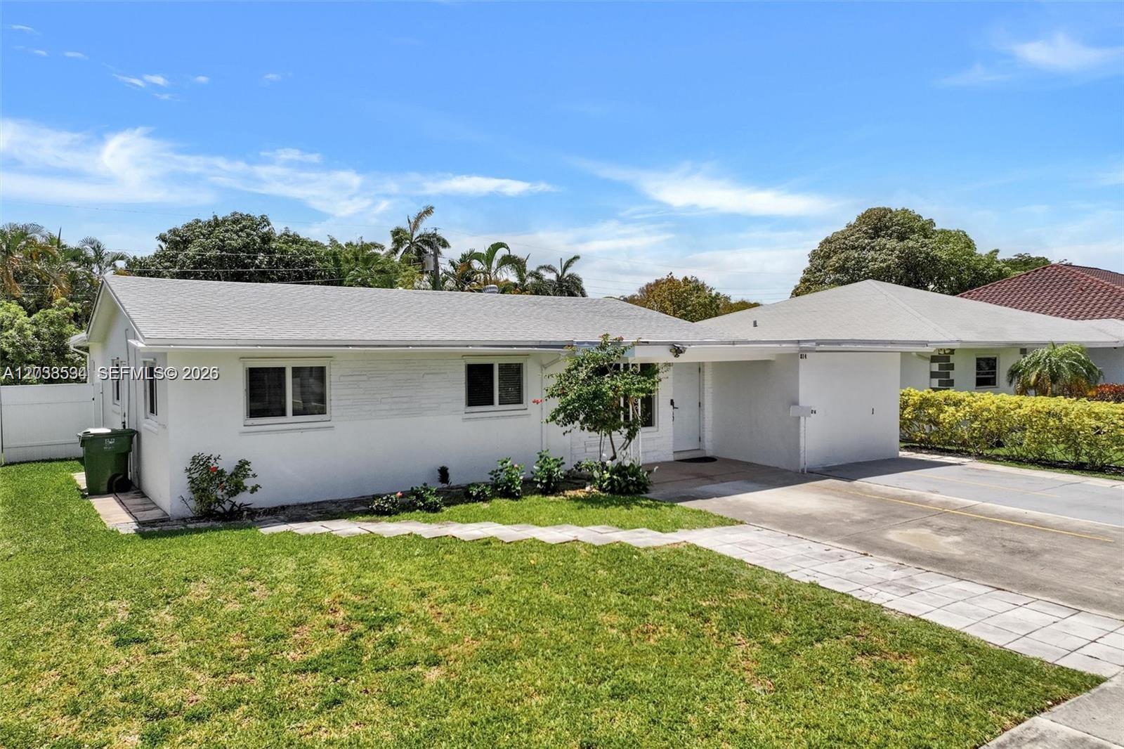 A white, single-story house features a gray shingled roof, a carport, and a front lawn — 814 NE 4th St, Hallandale Beach FL 33009, HALLANDALE BEACH, FL