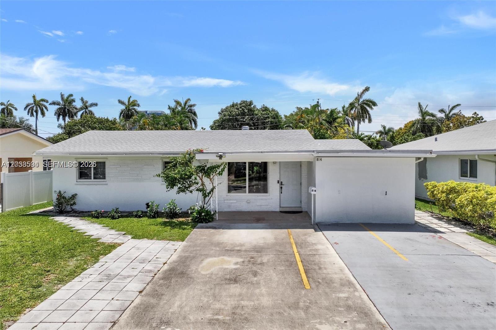 A white single-story house features a concrete driveway and a small front yard — 814 NE 4th St, Hallandale Beach FL 33009, HALLANDALE BEACH, FL