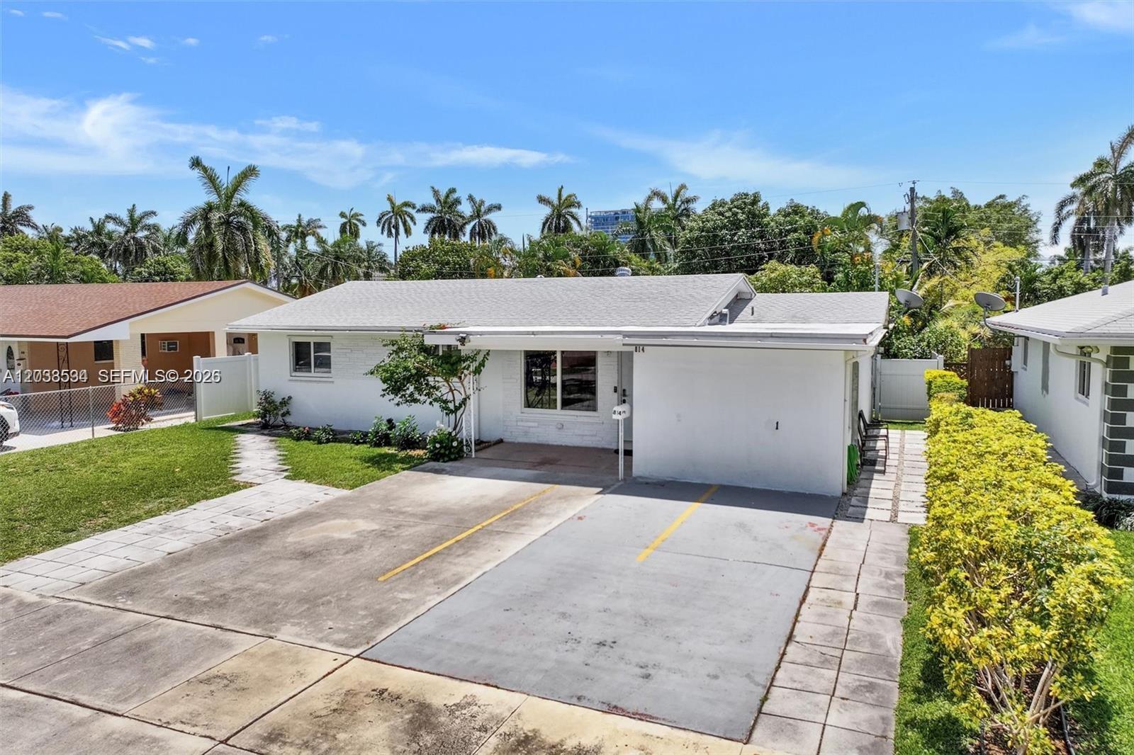 A white single-story house features a concrete driveway and a small front yard — 814 NE 4th St, Hallandale Beach FL 33009, HALLANDALE BEACH, FL