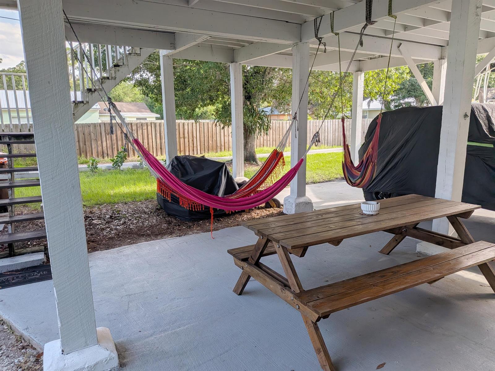 A covered patio features a wooden picnic table, two hanging hammocks, and a staircase — 1866 9th Place, Vero Beach FL 32960, VERO BEACH, FL