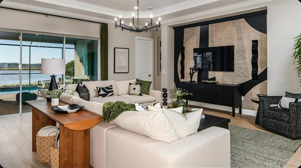 A living room features a large sectional sofa, a black media console, and a mural wall — 1039 TASSLEFLOWER TRAIL, ST CLOUD, FL