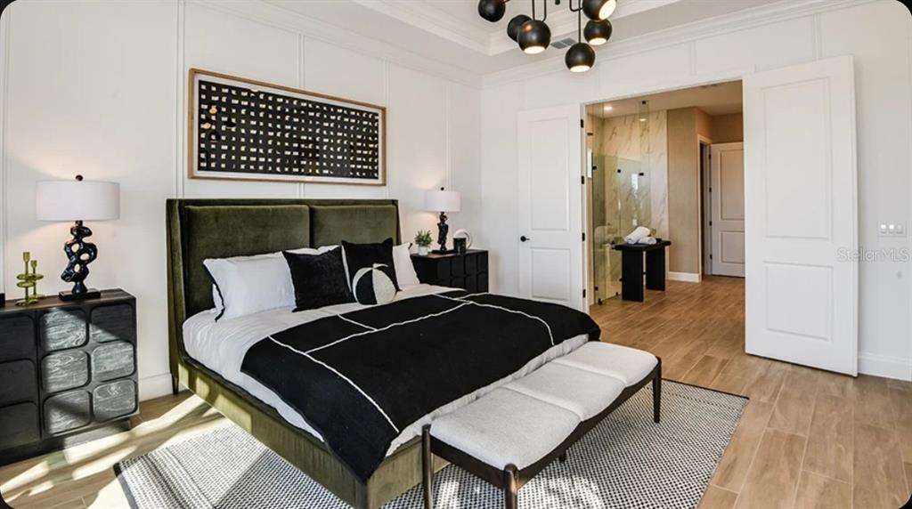 A bedroom features a green velvet bed, black and white bedding, and a modern chandelier — 1039 TASSLEFLOWER TRAIL, ST CLOUD, FL