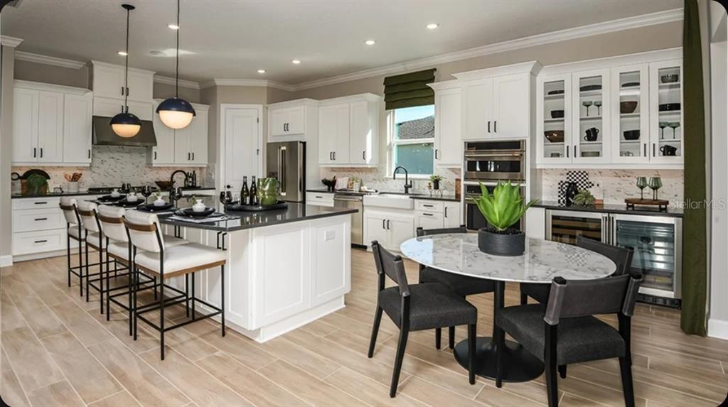 A bright kitchen features white cabinetry, a large center island, and a marble-topped dining table — 1039 TASSLEFLOWER TRAIL, ST CLOUD, FL