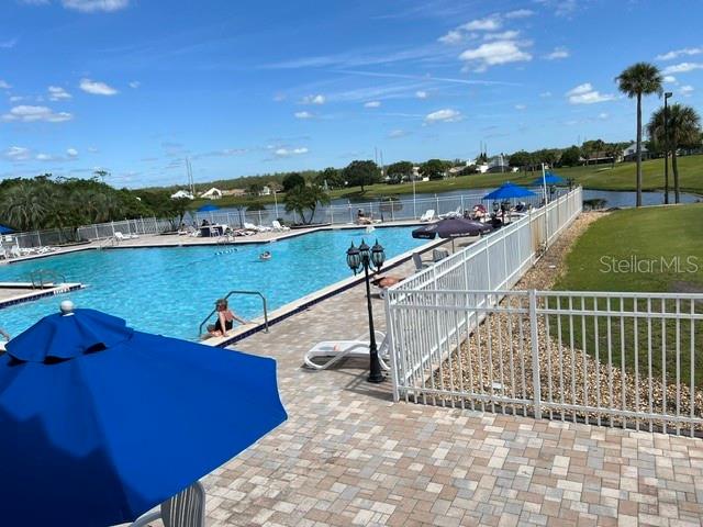 A swimming pool with lounge chairs and umbrellas overlooks a pond and golf course — 3912 ATRIUM DRIVE UNIT L7, ORLANDO, FL