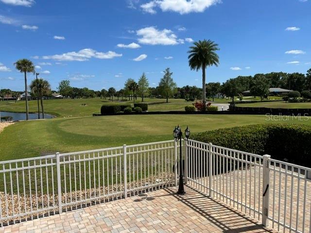A paved patio overlooks a golf course with palm trees and a pond under a blue sky — 3912 ATRIUM DRIVE UNIT L7, ORLANDO, FL