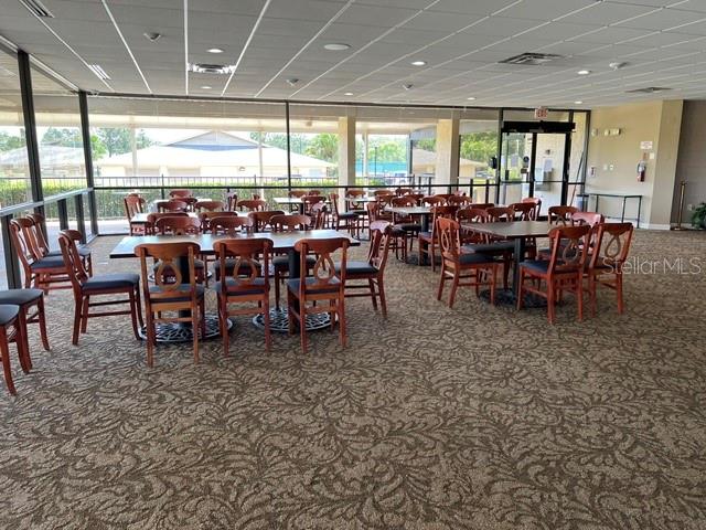 A spacious dining room features numerous tables and chairs on a patterned carpeted floor — 3912 ATRIUM DRIVE UNIT L7, ORLANDO, FL