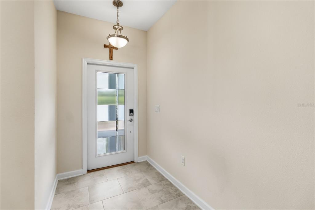 An entryway features a white front door with glass panels, tile flooring, and a pendant light — 12140 SONNET AVENUE, ORLANDO, FL