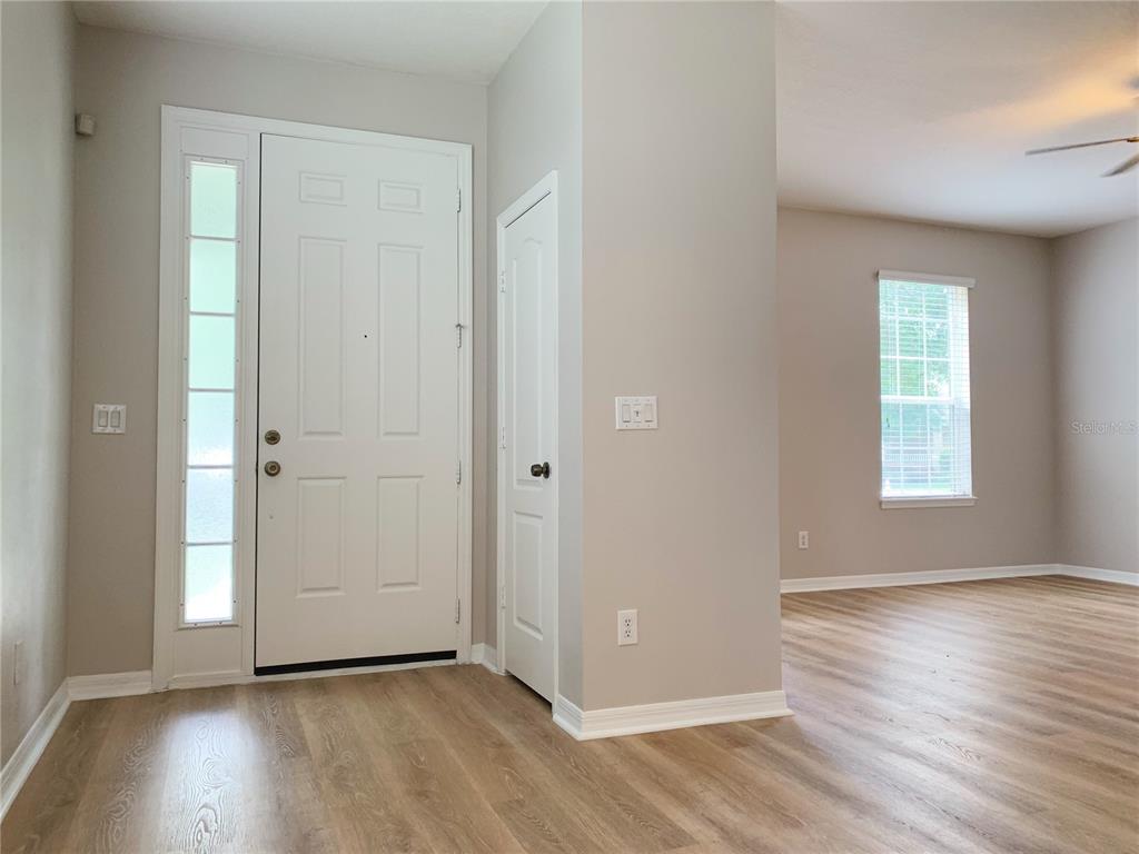 An entryway with a white front door, a side light, and light wood-look flooring — 10353 LAKE DISTRICT LANE UNIT 56C, ORLANDO, FL