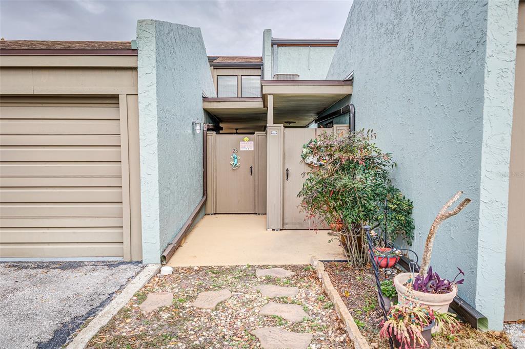 A light blue stucco townhouse exterior features a garage, a gated courtyard, and stone pavers — 2500 21ST STREET NW UNIT 23, WINTER HAVEN, FL