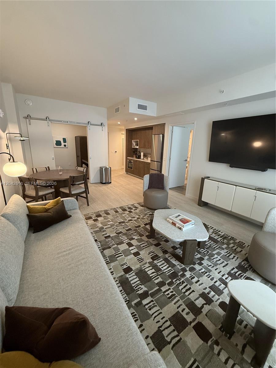 A modern living room features a sofa, patterned rug, television, and an adjacent dining area — 1611 SW 2nd Avenue # 202, Miami FL 33129, MIAMI, FL