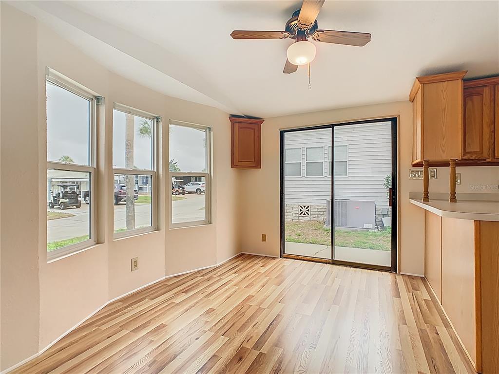 A dining area features wood-look flooring, a ceiling fan, large windows, and a sliding glass door — 9705 LAKE BESS ROAD UNIT 715, WINTER HAVEN, FL