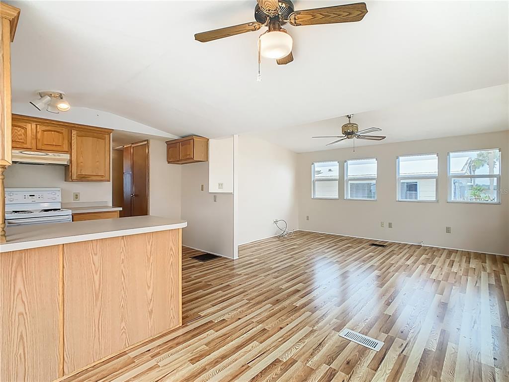 An open-concept living room and kitchen featuring wood-look flooring and two ceiling fans — 9705 LAKE BESS ROAD UNIT 715, WINTER HAVEN, FL